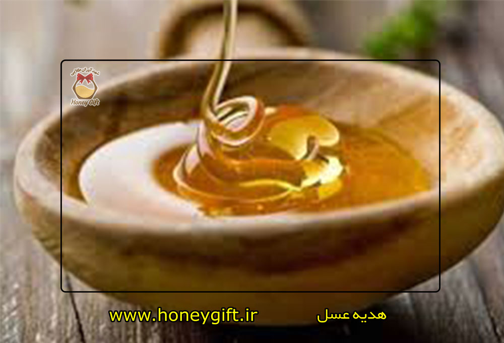 ریختن عسل گون در داخل کاسه چوبی عسل روی میز