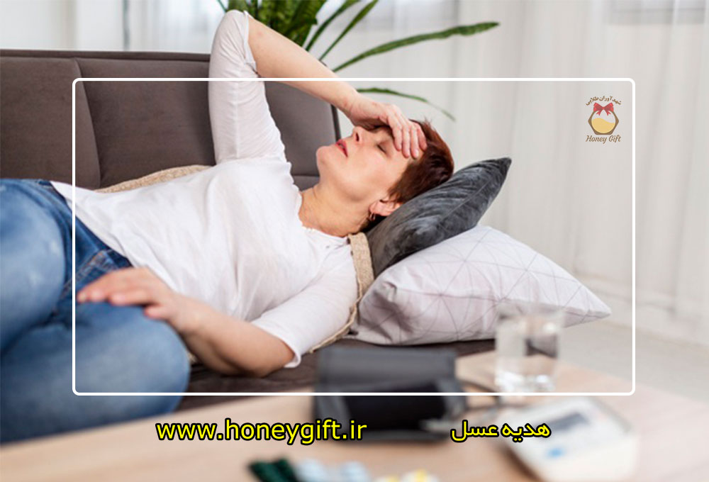 خانمی به دلیل فشار خون بالا و سر درد روی کاناپه دراز کشیده و دست بر سر دارد